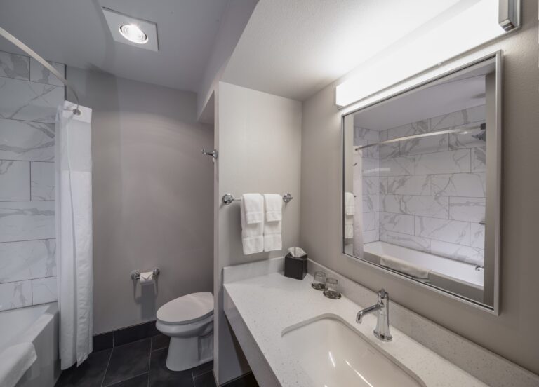 Wide view of a Double Queen bathroom showing the vanity, mirror and shower
