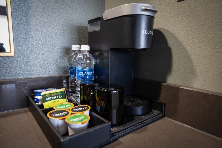 The in-room coffee station with a single-serve machine, bottled water, pods and tea on a tray