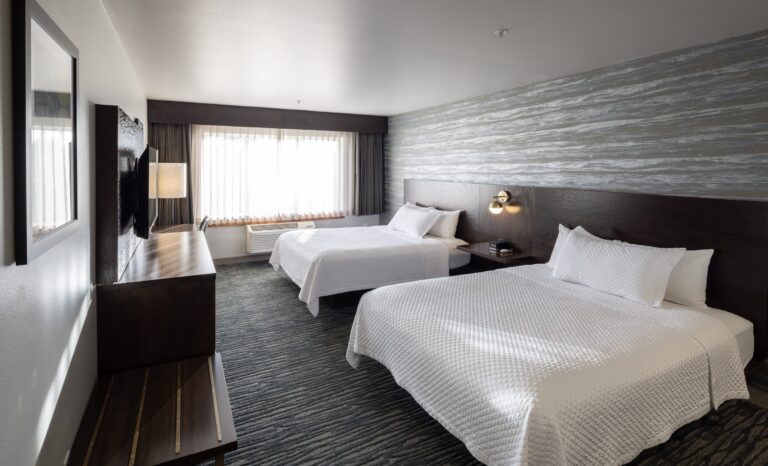 Panoramic view of a Double Queen room showing both beds and the window wall
