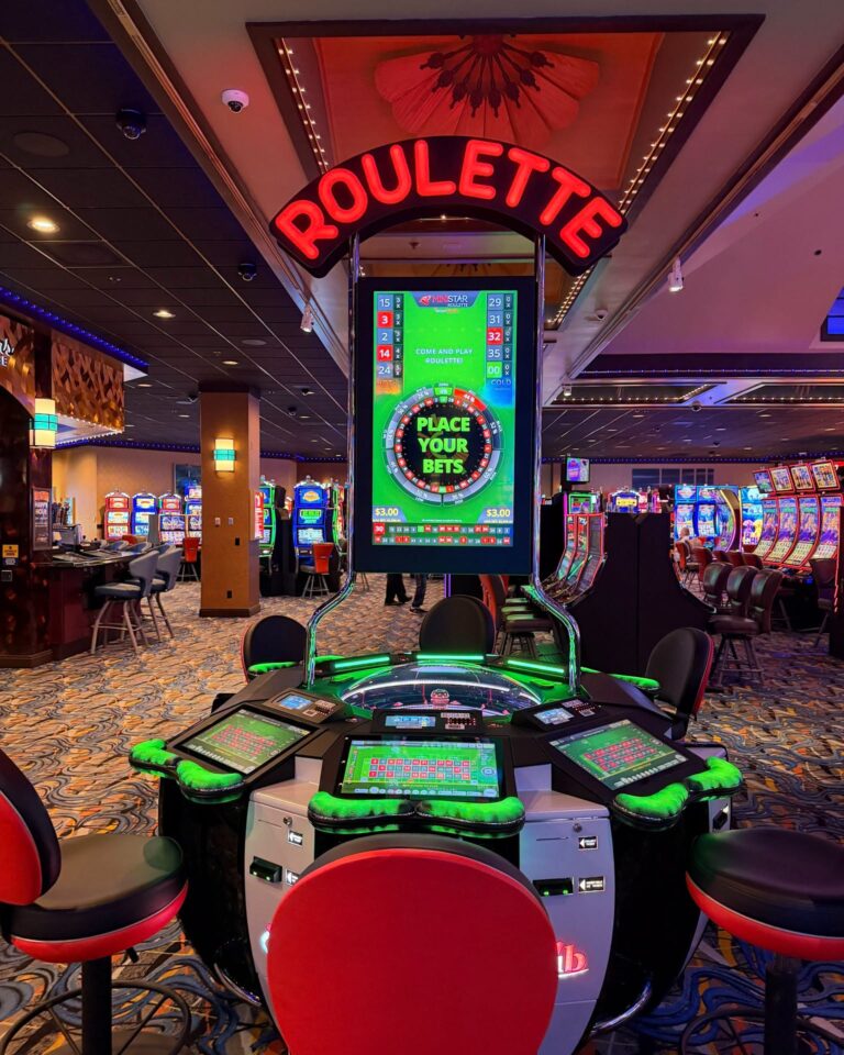 The Mini Star electronic roulette terminal on the casino floor, with a real wheel under a glass dome and player screens around it