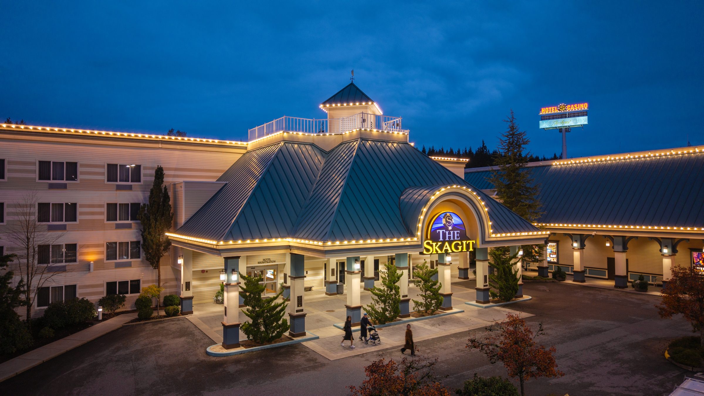 The Skagit Casino Resort at dusk, its teal pagoda roof and colonnaded entrance outlined in warm light