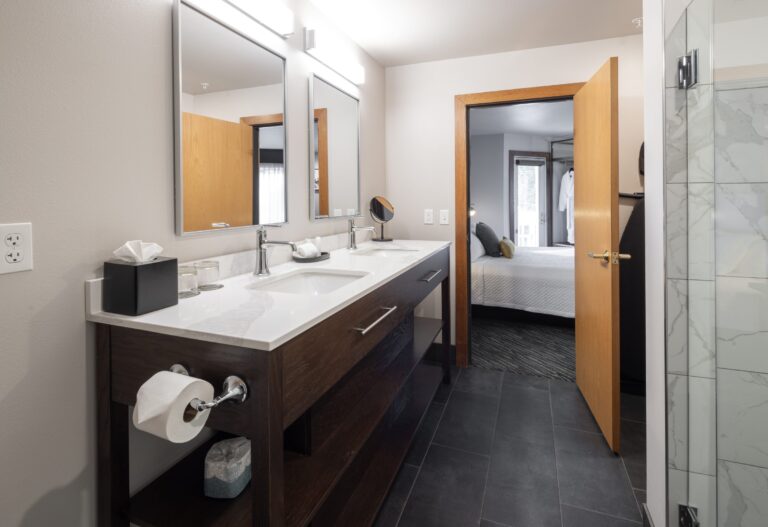 The King Suite bathroom with a wide vanity, framed mirror and tiled shower