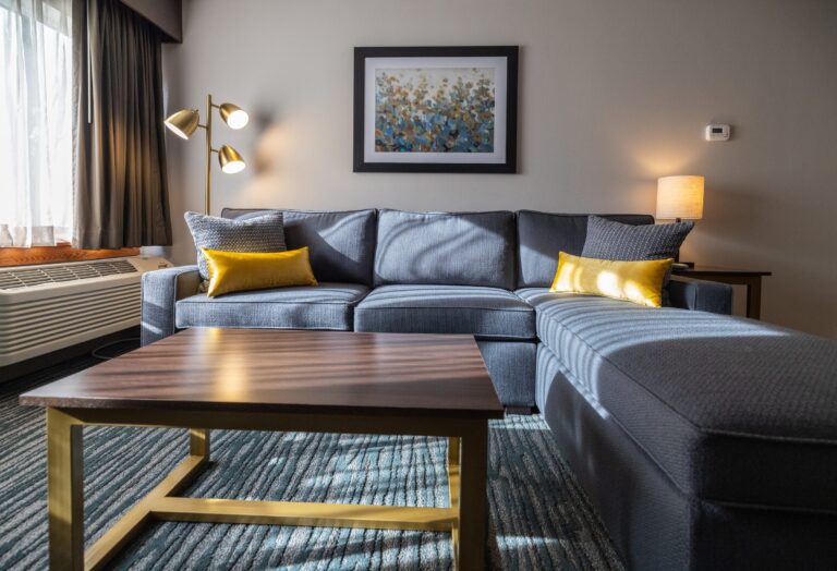 The King Suite living area with a grey sectional sofa, gold cushions, a timber coffee table and a framed print