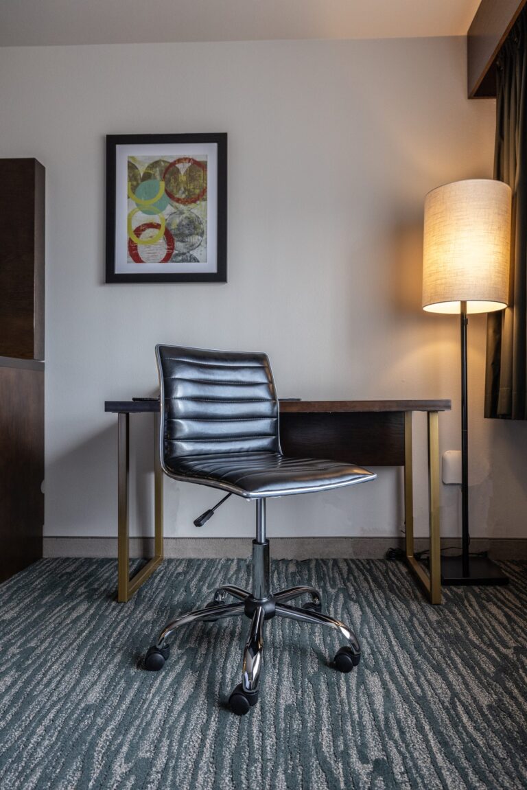 The work desk and ergonomic chair in a Single King room, with a floor lamp and framed artwork