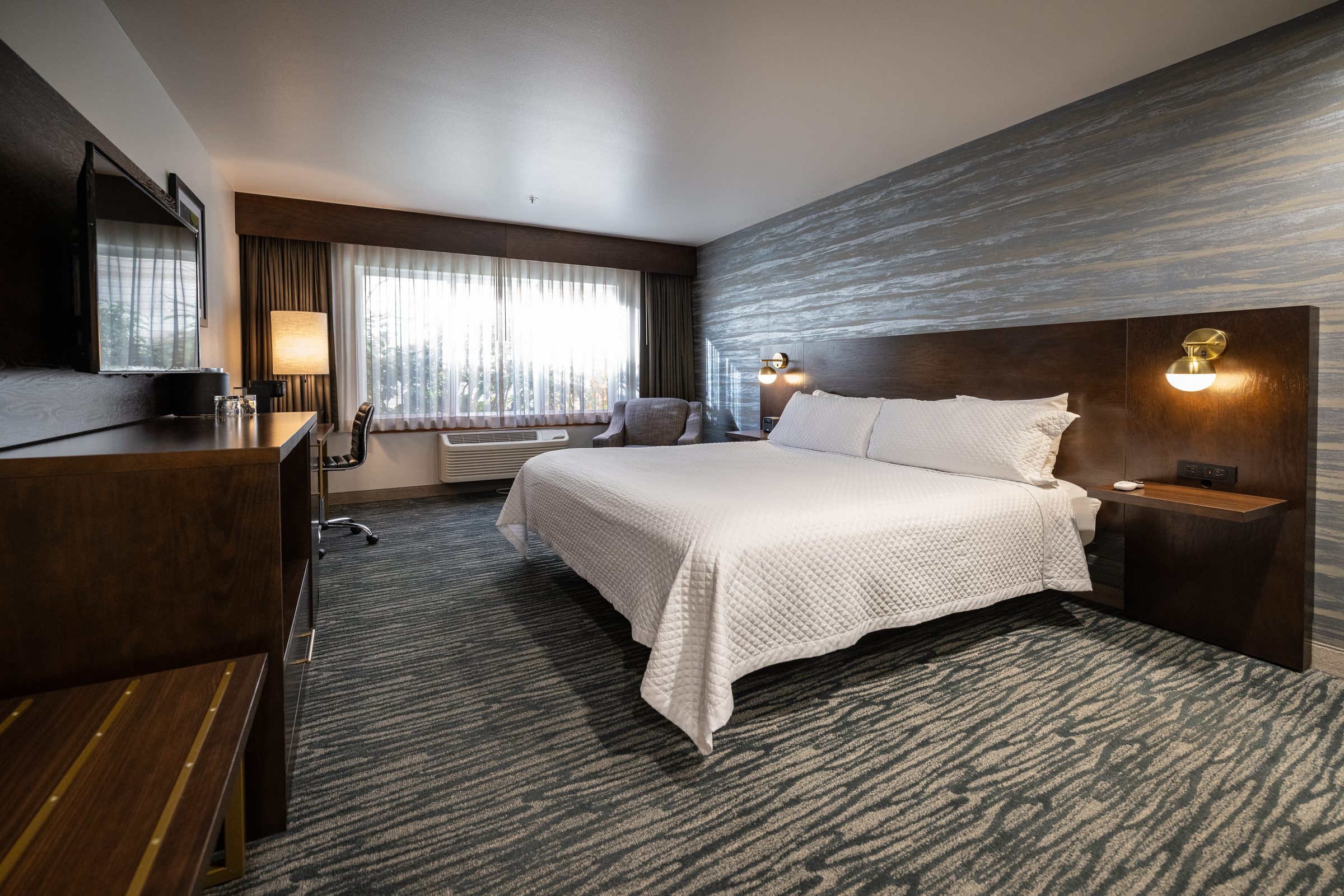 A Single King guest room with a king bed, upholstered headboard and a window to one side