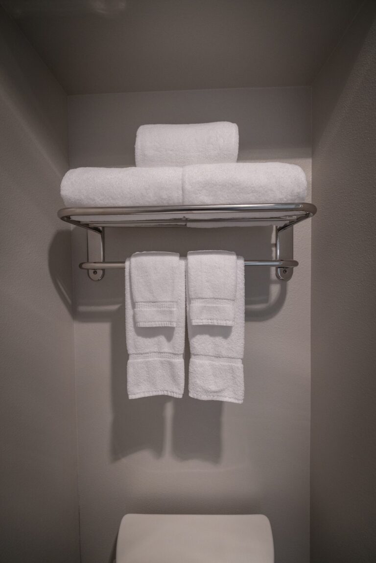 Folded white towels stacked on a chrome rail in a guest bathroom